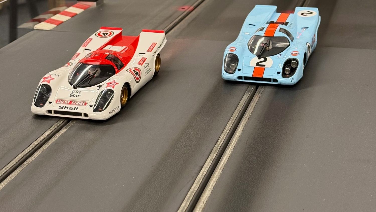 Zwei Porsche 917 im Massstab 1:32, weiss-rot und Gulf-Hellblau, nebeneinander auf der Rennbahn