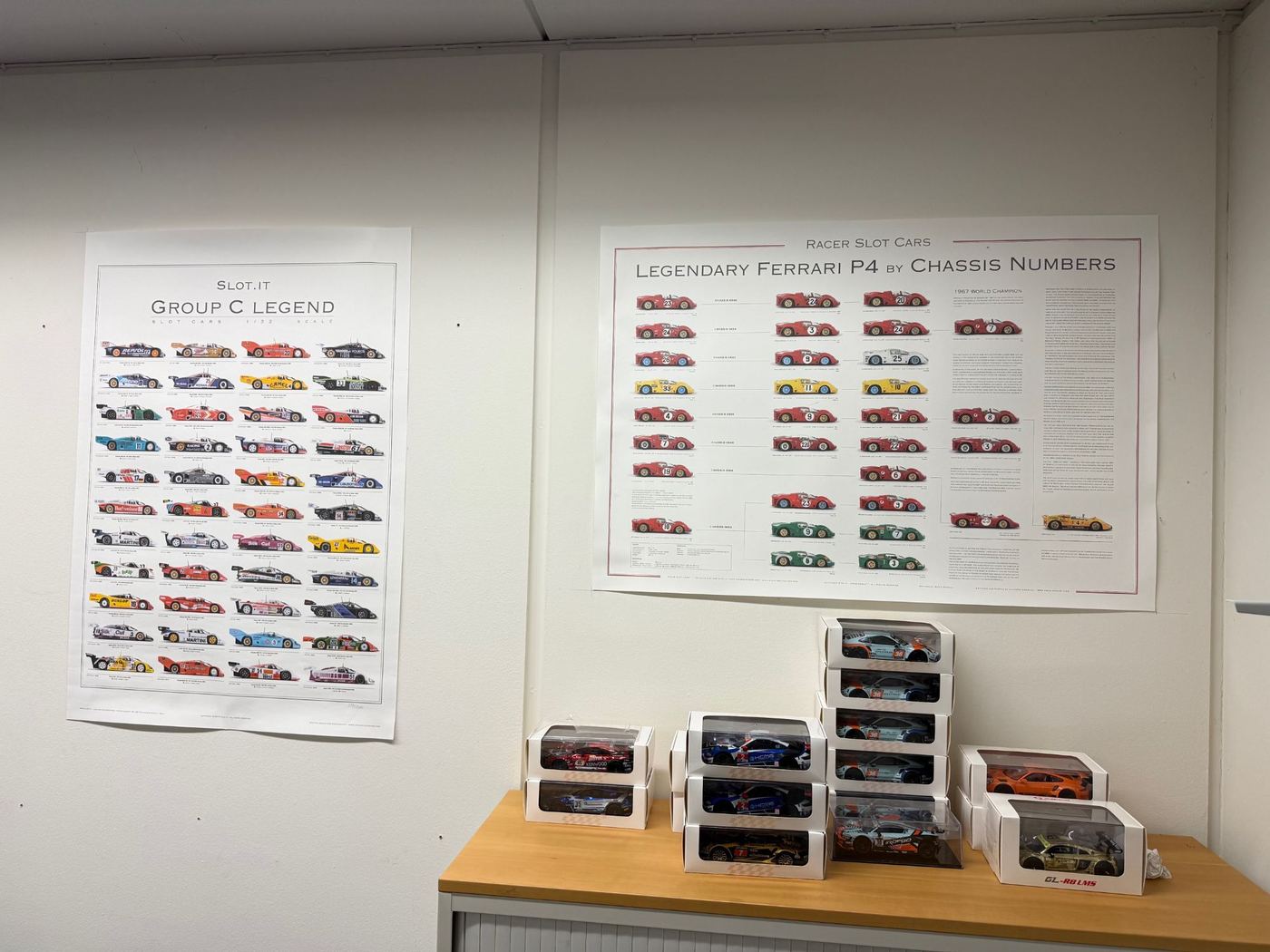 Poster «Group C Legend» und «Legendary Ferrari P4» an der Wand, darunter Modelle in Schachteln